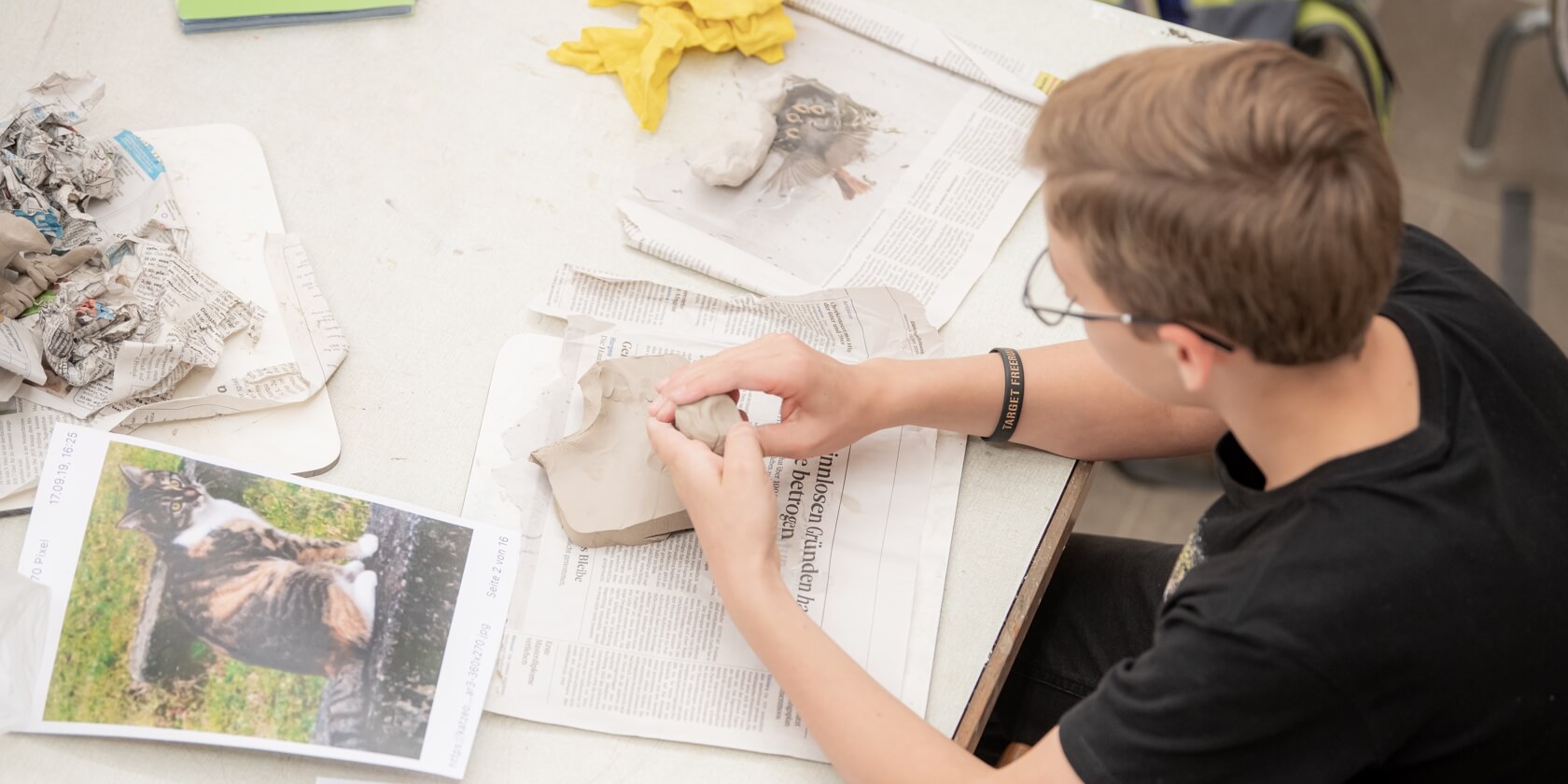 Ein Schüler im Kunstunterricht an seinem Tisch mit Ton in der Hand